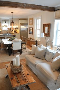 a living room filled with furniture next to a kitchen and dining room table in front of a window