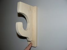 a person holding a wooden object with the letter c on it's side and pointing at it