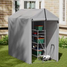 an outdoor storage shed with its doors open on the grass in front of a house