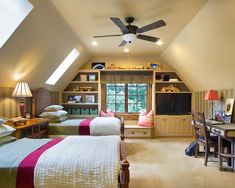 a bedroom with two beds and a desk in the corner under a slanted ceiling