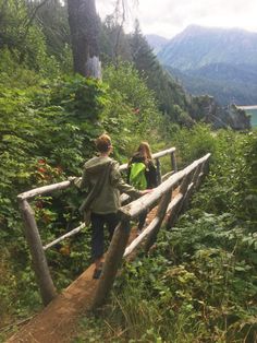 two people walking up a wooden path in the woods