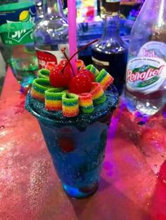 a colorful drink with fruit and candy on the rim