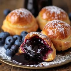 blueberry danish pastries on a plate with powdered sugar and fresh berries next to them