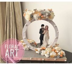 a bride and groom standing in front of a floral art photo frame on a table