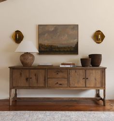 a table with two vases and a painting on the wall above it in a living room