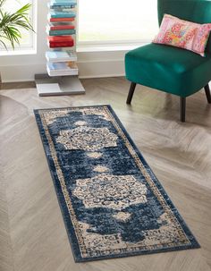 a blue area rug with an ornate design on the floor in front of a green chair