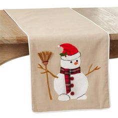 a table runner with a snowman holding a broom and wearing a santa claus hat