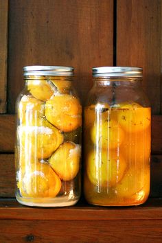 two jars filled with lemons sitting on top of a wooden table