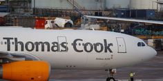 an orange and white jet airliner sitting on top of an airport tarmac with the words thomas cook written on it