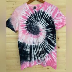 a pink and black tie - dye shirt hanging on a wooden wall