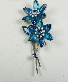 Vintage Juliana style aqua two flower brooch.  Brooch is composed of two flowers with aqua blue navette petals with a light sapphire rhinestone center surrounded by opaque white stones. Stem has a twisted texture with a light sapphire blue stone accent.  Rhinestones are unfoiled and prong set. Pin measures 3 x 1 1/4". Blue Diamond Gemstone Brooches, Vintage Blue Brooch Pin, Blue Floral Brooch Jewelry, Vintage Blue Diamond Brooches, Blue Crystal Brooches With Rhinestones, Blue Flower-shaped Jewelry Brooch, Light Sapphire, Scarf Pin, Shawl Pins