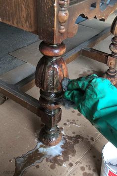 a green bag is sitting on the ground next to an old wooden table with peeling paint