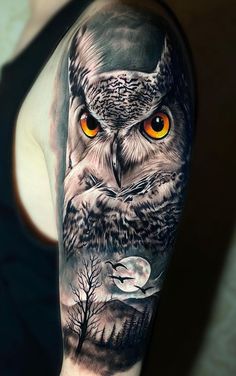 an owl with orange eyes and trees on his arm is shown in this tattoo design