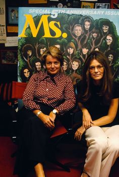 two women sitting next to each other in front of a poster