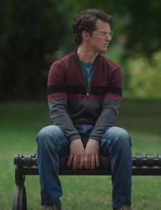 a man sitting on top of a bench in the park