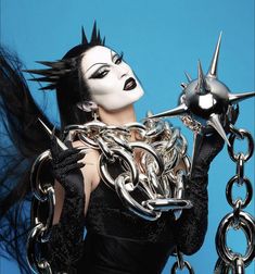 a woman with black and white makeup holding chains