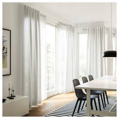 a dining room with white curtains and black chairs