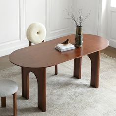 a wooden table sitting on top of a white rug next to a vase filled with flowers