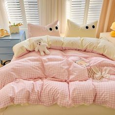 a bed with pink gingham comforter and two teddy bears sitting on it