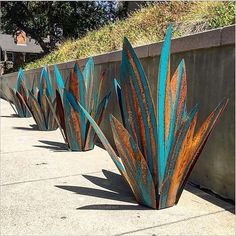 several metal planters sitting on the side of a road next to a cement wall