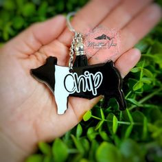 a hand holding a black and white cow shaped keychain with the word chip on it