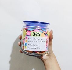 a person holding up a jar filled with colorful confetti and writing on it