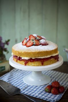 a cake sitting on top of a white plate covered in icing and strawberries