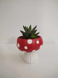 a potted plant sitting on top of a mushroom shaped container with white polka dots