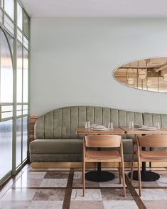 a table and two chairs in front of a couch with mirrors on the wall behind it