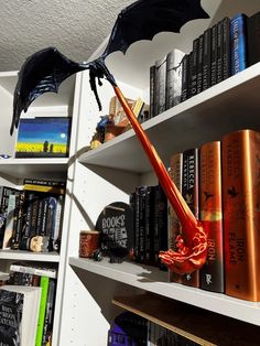 a book shelf filled with books and a dragon figurine on top of it