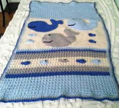 a crocheted baby blanket with an elephant and whale design on the bottom is laying on a bed