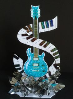 a blue guitar sitting on top of a crystal sculpture with music notes and piano keys