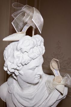 a white statue with high heels on it's head and a bow around the shoe