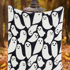 a black and white blanket with ghost faces on it, surrounded by jack - o - lantern pumpkins