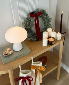 a table topped with candles next to a christmas wreath and other items on top of it