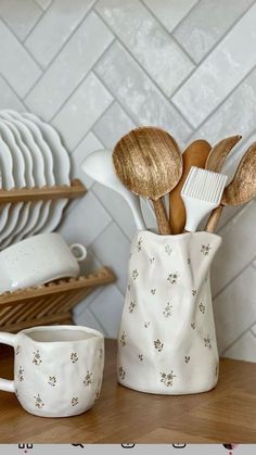 a white vase filled with lots of wooden spoons