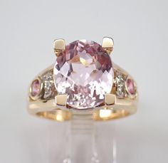 14K Yellow Gold Diamond, Pink Sapphire and Kunzite Ring. This ring is set in the center with one genuine Oval Kunzite. This Kunzite measures 12 X 10 mm and weighs 3 1/2 carat.  There are two Round Pink Sapphires bezel set in this ring, these gemstone weigh a total of .30 carat.  There are also twelve genuine Round Brilliant Diamonds set in the ring. These diamonds are H color, SI/I clarity and weigh a total of .08 carat. This ring is 14KT Yellow Gold, weighs 9.0 grams and is a finger size 7, which can be resized (please inquire about sizing with the finger size you need). This ring will be accompanied by an appraisal written by a GIA Certified Diamond Grader with the retail replacement value of $3,695.00. I will ship this ring promptly in a beautiful gift box. ADDITIONAL REQUESTS If you wo Yellow Gold Morganite Jewelry With Diamond Accents, Morganite Multi-stone Jewelry For Anniversary, Morganite Multi-stone Jewelry For Anniversaries, Morganite Multi-stone Anniversary Rings, Morganite Multi-stone Rings For Anniversary, Morganite Multi-stone Wedding Jewelry, Formal Sapphire Ring With Morganite Accent Stones, Formal Morganite Sapphire Ring With Accent Stones, Kunzite Ring