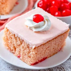 a piece of cake on a plate with cherries in the bowl next to it