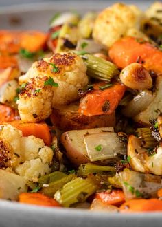 a white bowl filled with cauliflower, carrots and other veggies