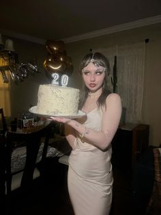 a woman holding a cake with the number 20 on it