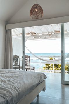 a bed sitting next to a window with a view of the ocean on it's side