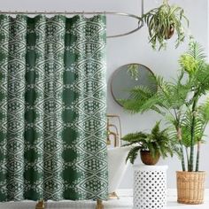 a green shower curtain in a bathroom next to potted plants and a bathtub