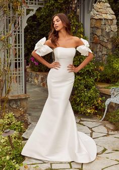 a woman in a white wedding dress posing for the camera with her hands on her hips