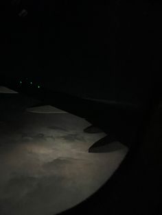 the wing of an airplane at night with lights in the sky and clouds below it