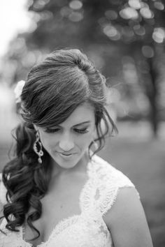 a woman in a wedding dress is looking down at her hair and wearing large earrings