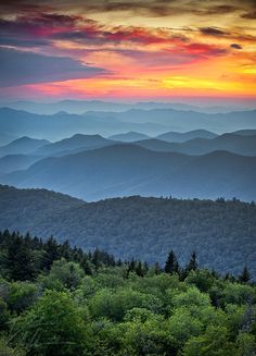 the mountains are covered in colorful clouds at sunset