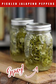 two jars filled with pickles sitting on top of a wooden table