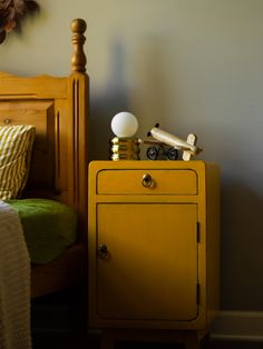 a yellow cabinet sitting on top of a bed next to a wooden headboard and night stand