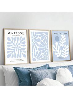 three blue and white posters on the wall above a bed