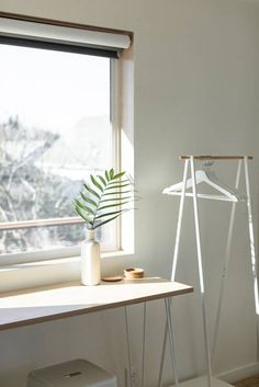 a white table with a plant on it next to a window